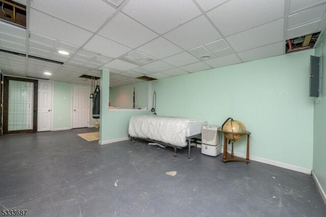 basement featuring a drop ceiling and electric panel