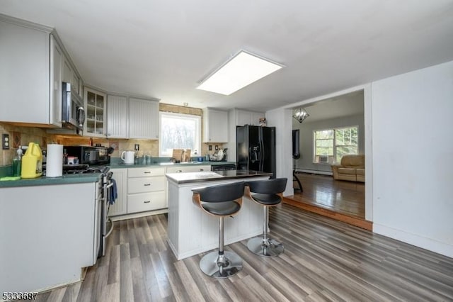 kitchen with white cabinetry, dark hardwood / wood-style flooring, a kitchen island, and black appliances