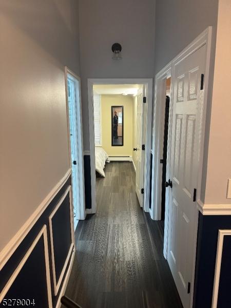 hallway with a baseboard heating unit and dark hardwood / wood-style floors