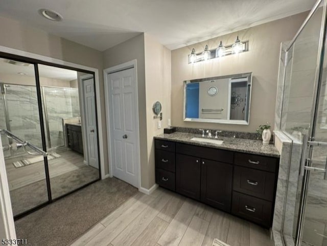 bathroom featuring hardwood / wood-style floors, vanity, and a shower with door