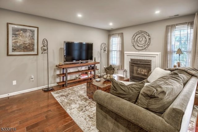 living room featuring a fireplace, dark hardwood / wood-style floors, and a healthy amount of sunlight