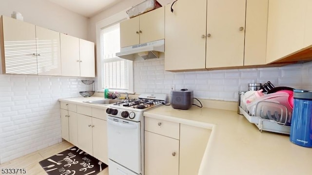 kitchen with light tile patterned floors, gas range gas stove, white cabinetry, and sink