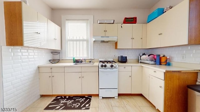 kitchen featuring tasteful backsplash, cream cabinetry, sink, and white gas range oven