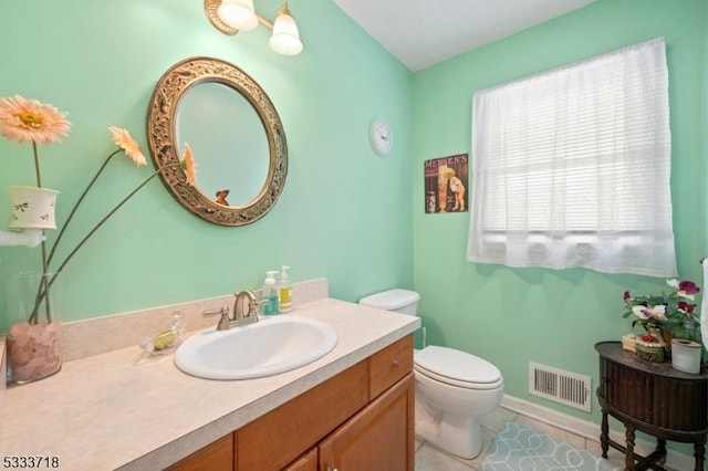 bathroom with tile patterned flooring, toilet, vanity, visible vents, and baseboards