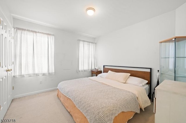 bedroom with baseboards and light colored carpet