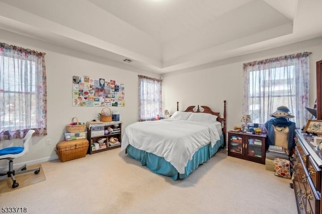 carpeted bedroom with baseboards, multiple windows, and a tray ceiling