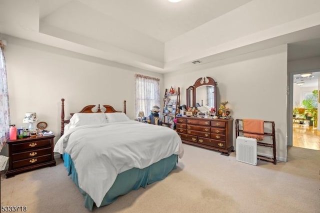 bedroom featuring a raised ceiling and light colored carpet