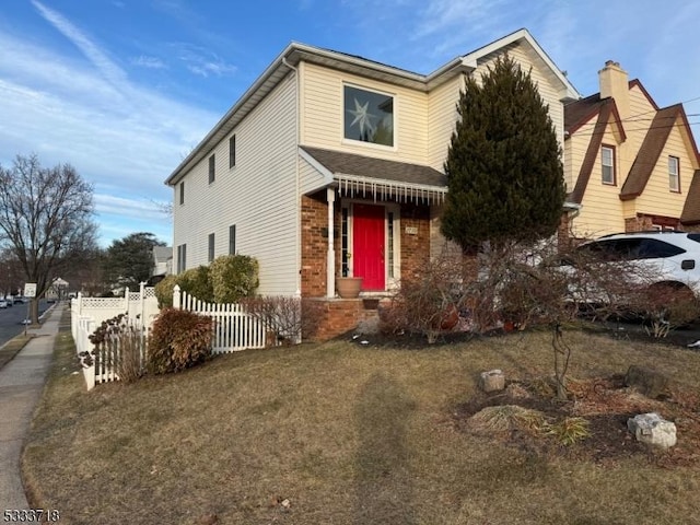 view of front of home featuring brick siding, a front lawn, and fence