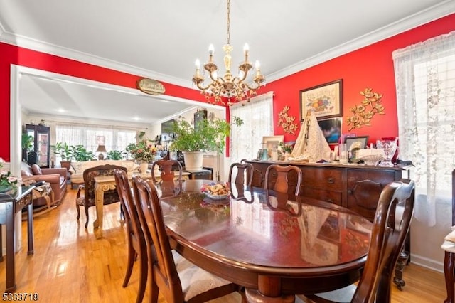 dining space with ornamental molding, a notable chandelier, and wood finished floors