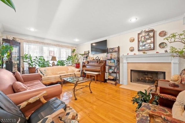 living room featuring ornamental molding, recessed lighting, a fireplace with raised hearth, and wood finished floors