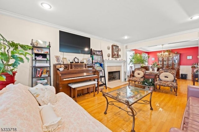 living room featuring a fireplace, a chandelier, crown molding, and wood finished floors