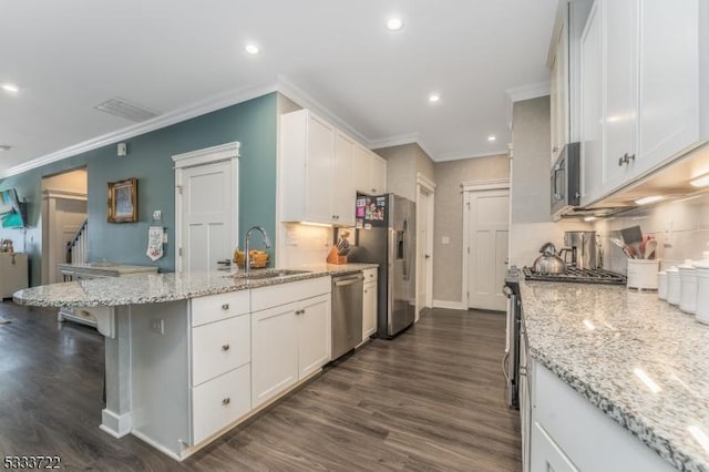 kitchen featuring a peninsula, a sink, stainless steel appliances, white cabinetry, and crown molding