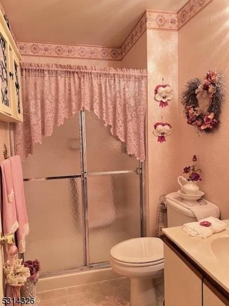 bathroom featuring an enclosed shower, vanity, tile patterned flooring, and toilet