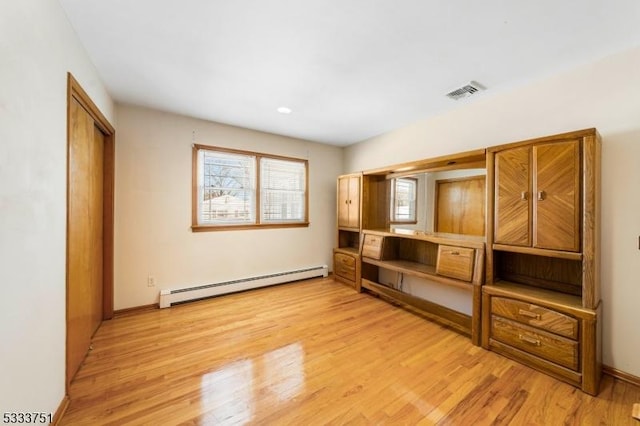 unfurnished living room featuring a baseboard heating unit and light hardwood / wood-style flooring