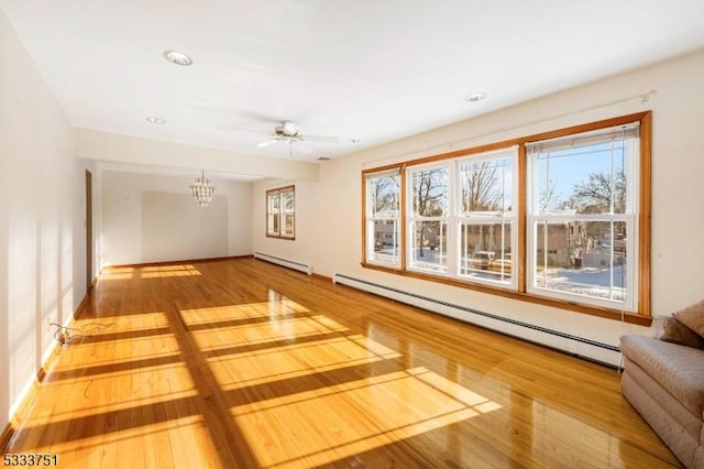 unfurnished living room with hardwood / wood-style flooring, ceiling fan with notable chandelier, and baseboard heating