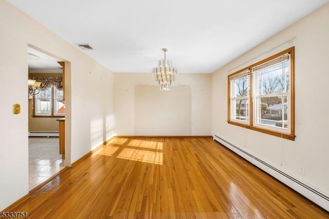 empty room featuring a baseboard radiator, wood-type flooring, and a chandelier