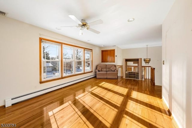 living room featuring ceiling fan with notable chandelier, hardwood / wood-style floors, and baseboard heating