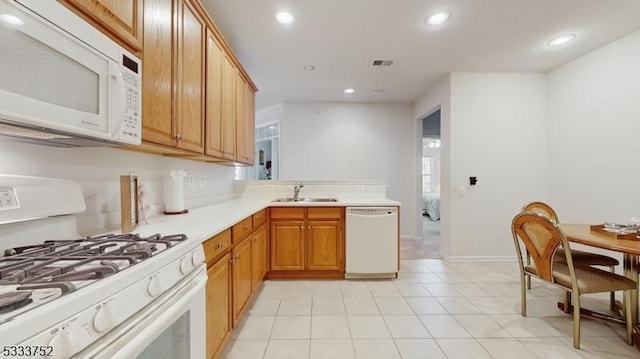 kitchen featuring white appliances, kitchen peninsula, sink, and light tile patterned floors