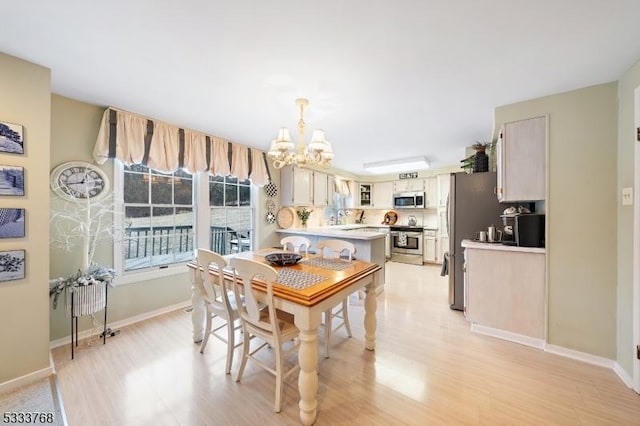 dining room featuring a notable chandelier, light hardwood / wood-style floors, and sink