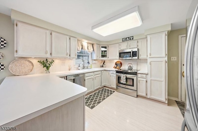 kitchen featuring sink, stainless steel appliances, white cabinetry, and backsplash