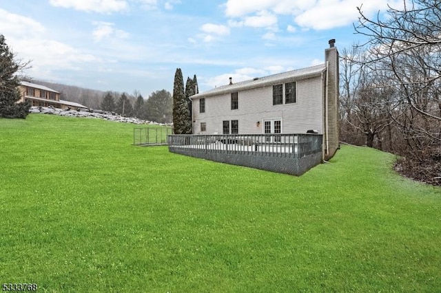 rear view of property with a wooden deck and a lawn