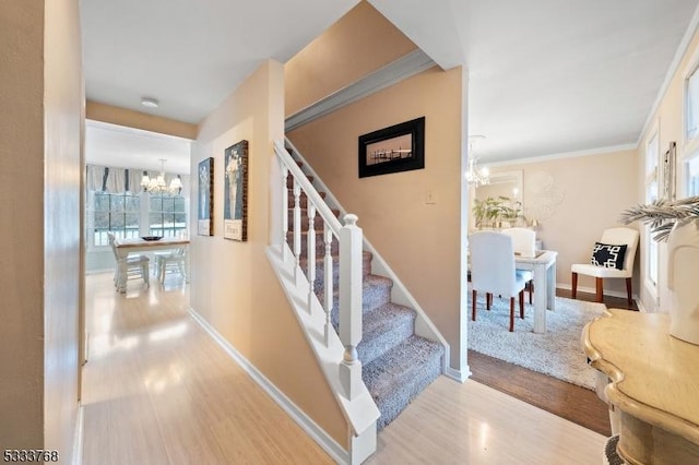 stairway with wood-type flooring and a chandelier