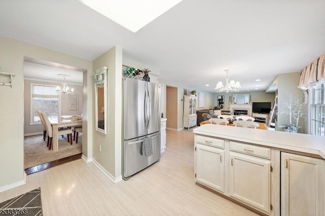 kitchen featuring an inviting chandelier, pendant lighting, light wood-type flooring, and stainless steel refrigerator