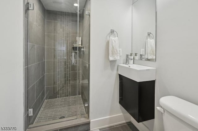 bathroom featuring a shower with door, toilet, and vanity