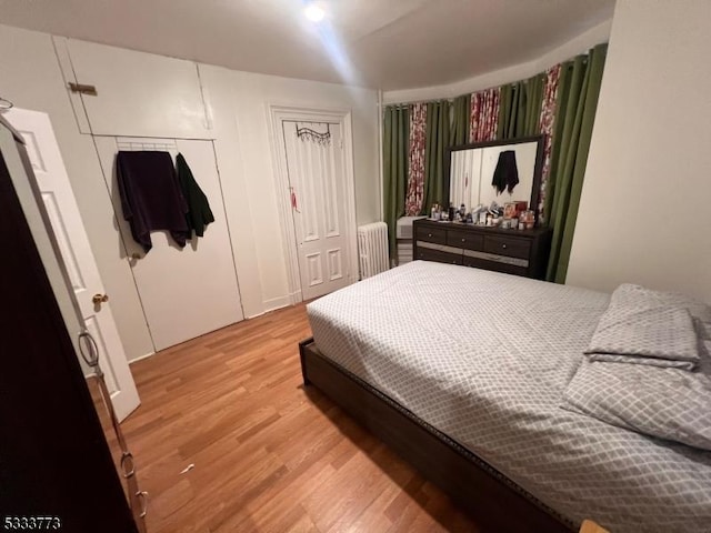 bedroom featuring radiator heating unit, wood-type flooring, and a closet