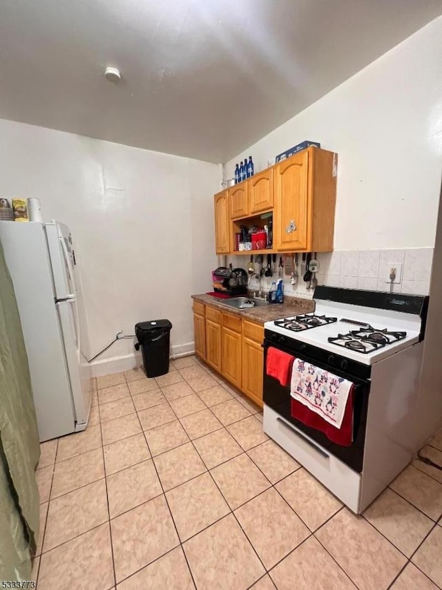 kitchen featuring sink, white appliances, light tile patterned floors, and decorative backsplash