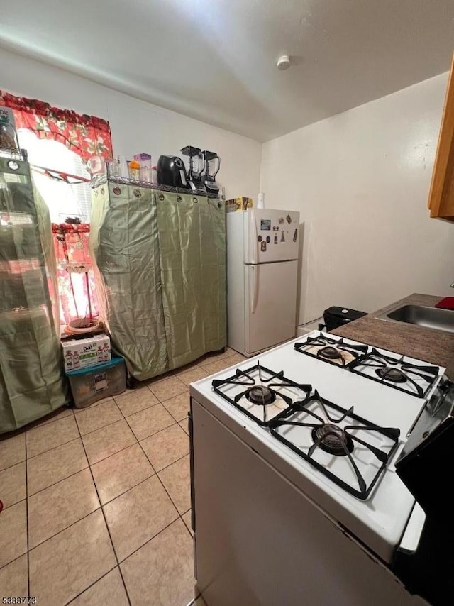 kitchen featuring sink, white appliances, and light tile patterned floors