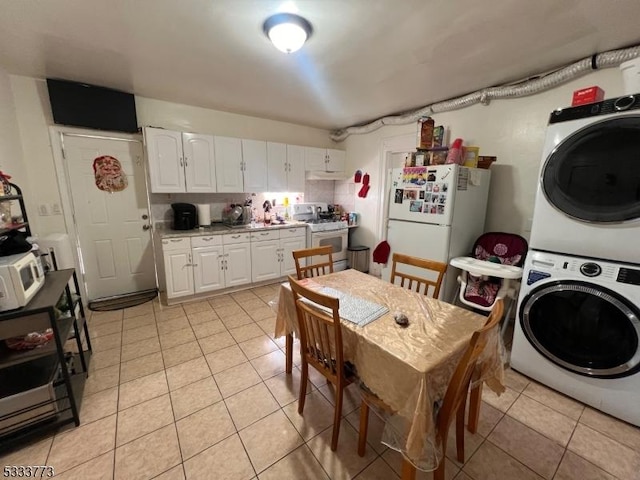 kitchen featuring white cabinetry, white appliances, light tile patterned floors, and stacked washer and dryer