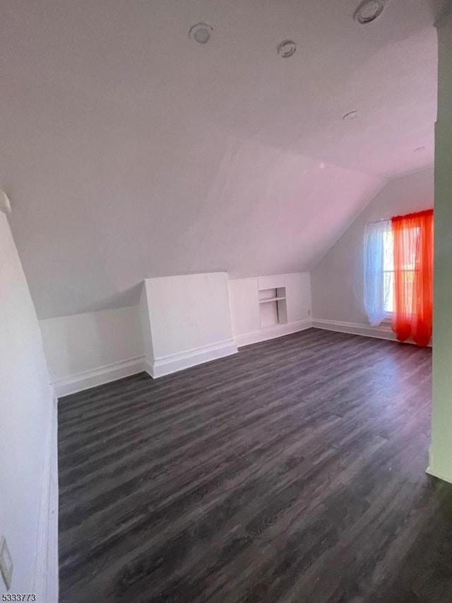 additional living space with dark hardwood / wood-style floors and vaulted ceiling