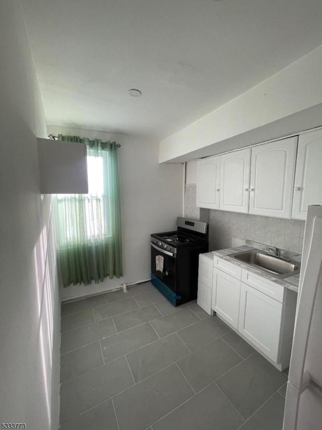 kitchen with sink, white cabinets, dark tile patterned flooring, and range with gas cooktop