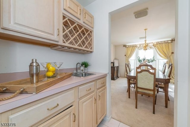 kitchen with sink, pendant lighting, light colored carpet, and a chandelier