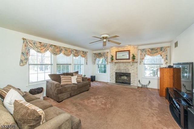 living room featuring a brick fireplace, a wealth of natural light, ceiling fan, and carpet flooring