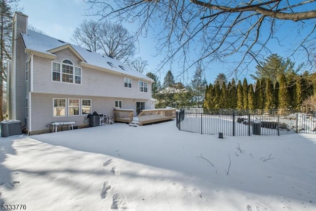 snow covered rear of property featuring a wooden deck and central AC unit