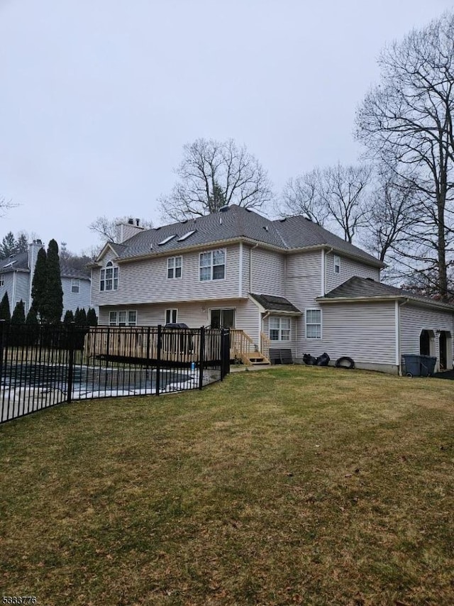 rear view of property with a pool side deck and a lawn