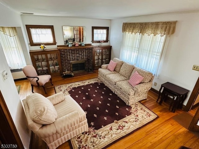 living room with hardwood / wood-style flooring, a brick fireplace, and radiator heating unit