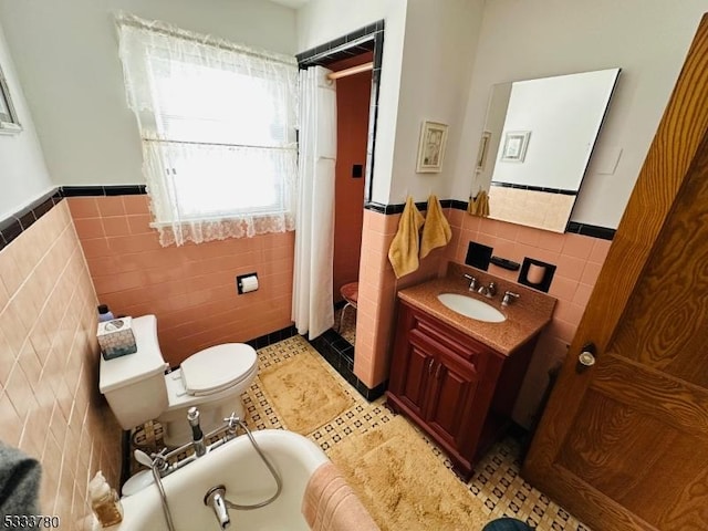 bathroom featuring toilet, tile walls, vanity, a tub, and tile patterned flooring