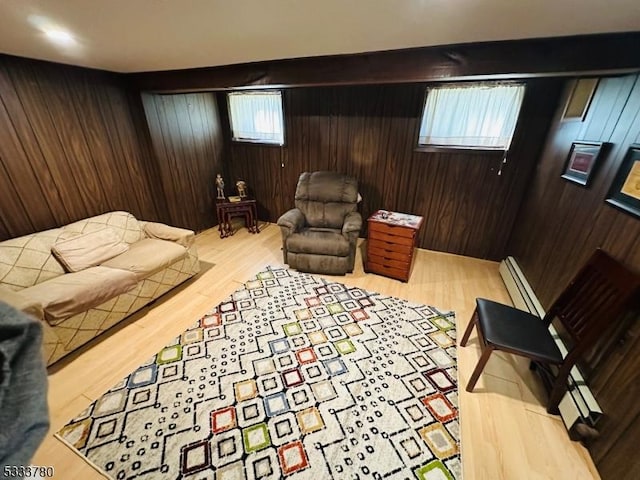 sitting room with a baseboard radiator, light hardwood / wood-style floors, and wood walls