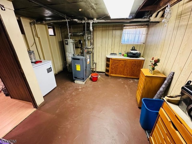 basement featuring wood walls, refrigerator, and gas water heater