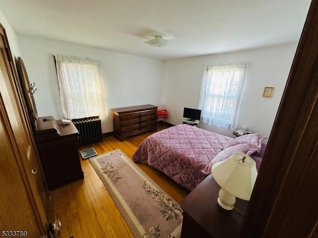 bedroom with radiator heating unit and light wood-type flooring