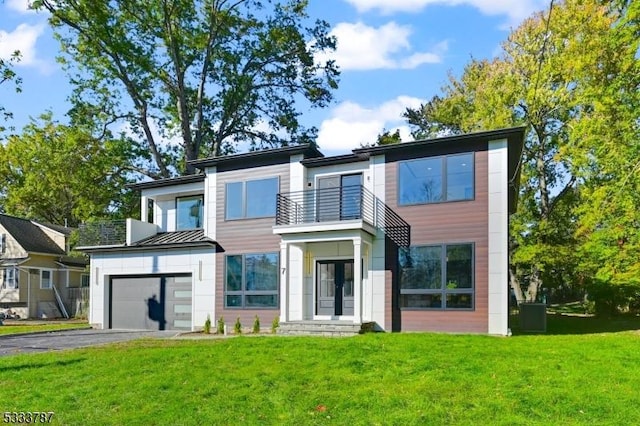 view of front of property featuring a garage, a balcony, and a front yard