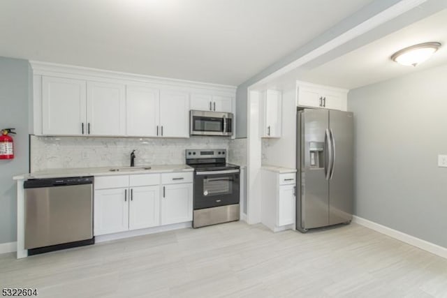 kitchen with appliances with stainless steel finishes, sink, decorative backsplash, and white cabinets