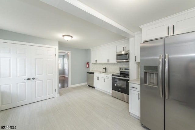 kitchen featuring tasteful backsplash, light hardwood / wood-style floors, white cabinets, and appliances with stainless steel finishes