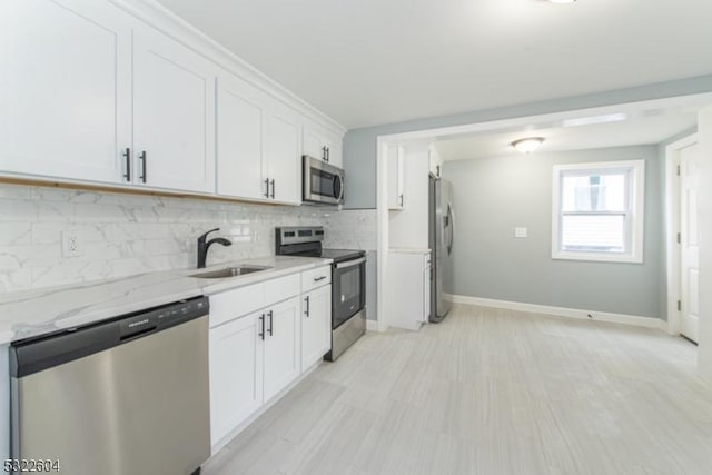 kitchen with sink, tasteful backsplash, stainless steel appliances, light stone countertops, and white cabinets