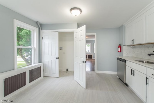 kitchen featuring tasteful backsplash, sink, dishwasher, and white cabinets