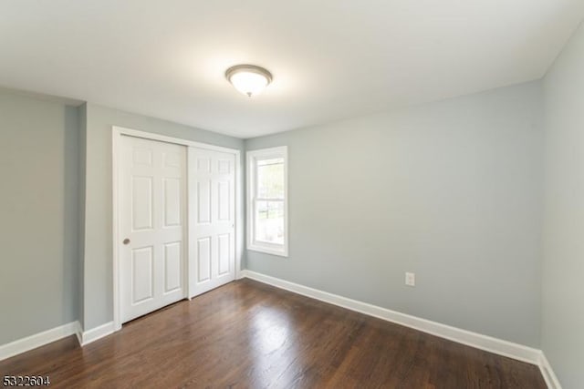 unfurnished bedroom with dark hardwood / wood-style flooring and a closet