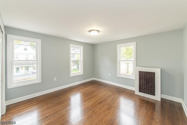 unfurnished living room with dark hardwood / wood-style flooring and a healthy amount of sunlight